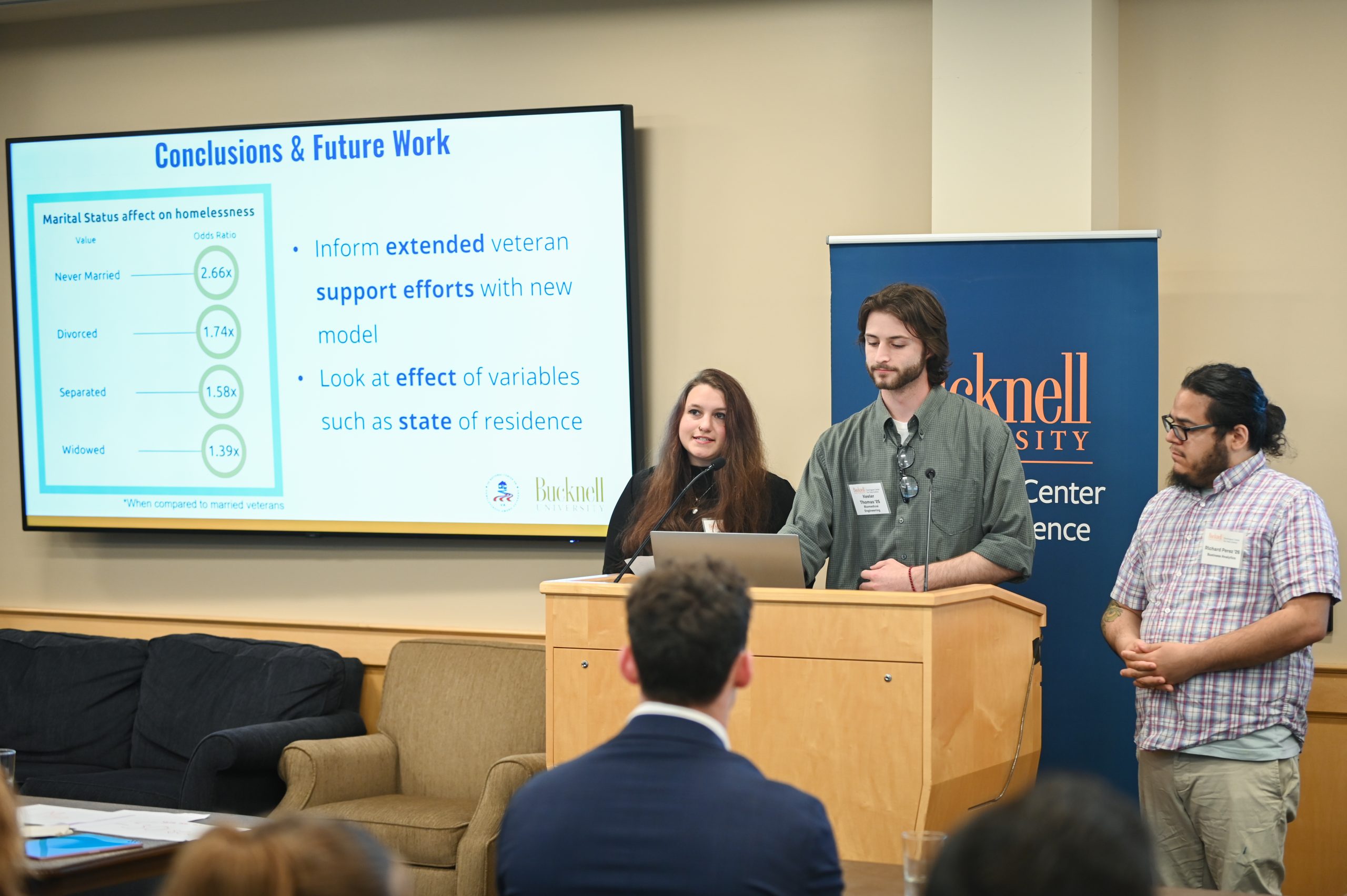 Claire Engel and Gwen Radecki standing behind a podium next to a screen that reads, "Acomplishments."