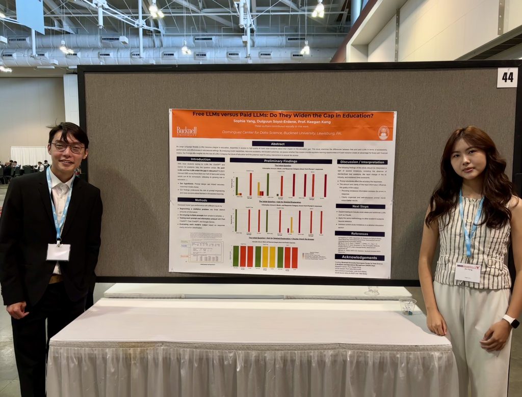 Sophie Yang and Dulguun Soyol-Erdene stand in a large conference center with their research post in between them posted on a large bulletin board.